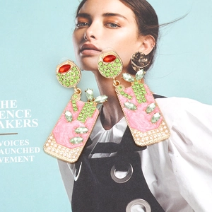 Boucles d'oreilles verre à cocktail roses avec strass et perles sur fond magazine