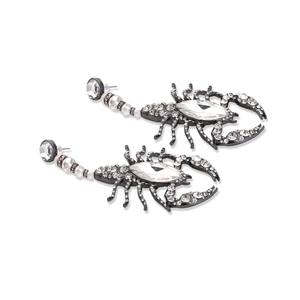 Exaggerated gunmetal scorpion drop earrings with sparkling crystals and a white background