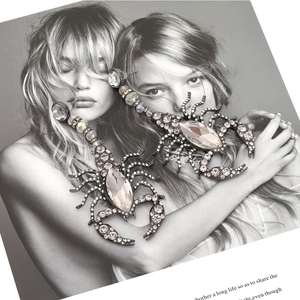 Dramatic scorpion drop earrings with sparkling rhinestones on a stylish magazine background