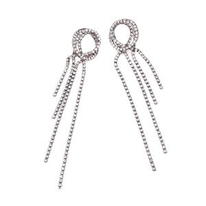 Détail de boucles d'oreilles pendantes argentées avec pompons en strass et clous ronds
