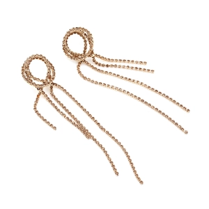 Gros plan de boucles d'oreilles dorées à pompons avec cercles et strass brillants