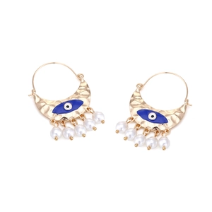 Detailed view of bohemian gold crescent earrings with blue evil eye enamel and pearls