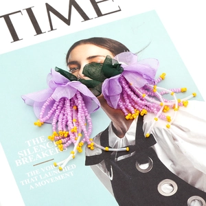 Exaggerated bohemian purple chiffon flower earrings with long beaded tassels on a magazine