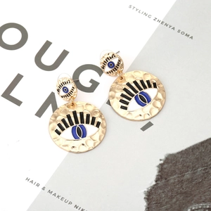 Vintage gold evil eye earrings with blue enamel and hammered texture in magazine style