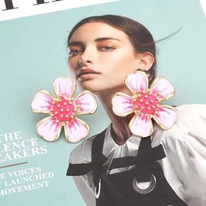 Sweet pink flower stud earrings with gold trim on a stylish magazine background