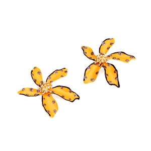Detail of floral earrings with orange enamel, polka dots, and golden stamen accents
