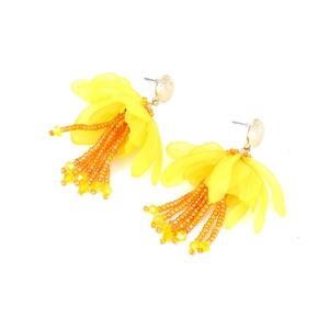 Dettaglio di orecchini a fiore in resina gialla con nappe di perline e borchie dorate