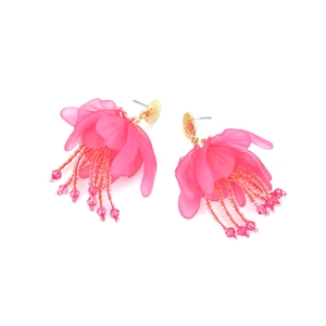 Dettaglio di orecchini a fiore in resina rosa con nappe di perline e borchie dorate