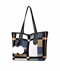 Detail of blue and white checkered tote bag featuring a white fluffy pompom charm