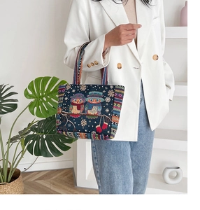 Detail shot of navy canvas tote bag with embroidered owl patterns and striped handles