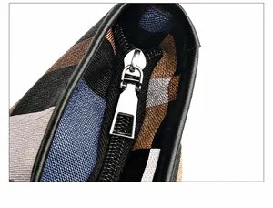 Close-up of silver metal zipper puller on a striped fabric shoulder bag with leather trim