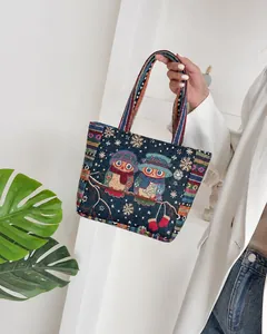 Detailed embroidery of ethnic owls and snowflakes on blue canvas tote shopping bag