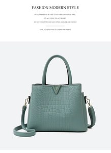 Close-up of cyan crocodile pattern handbag featuring a gold V-shaped buckle and strap