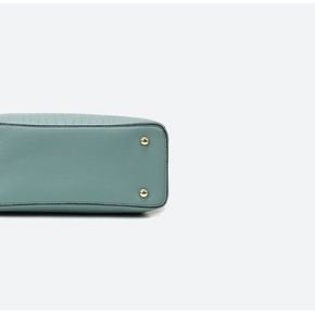 Close-up of golden metal studs on the bottom of a light blue leather handbag