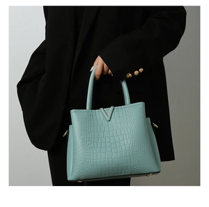 Detail of light blue crocodile embossed leather tote with metallic V-shaped buckle