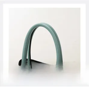 Detail of teal lychee grain leather handles with precise stitching on a designer handbag