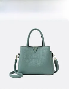 Close-up of cyan crocodile pattern leather handbag with gold V-shape metal accessory