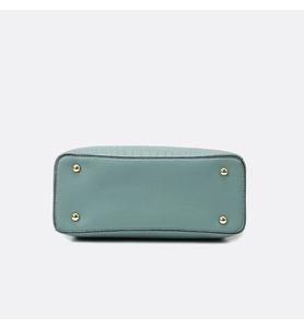Detailed base view of light blue handbag featuring crocodile texture and gold protective studs