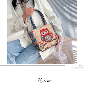 Detail of owl embroidery and colorful striped straps on the canvas tote bag