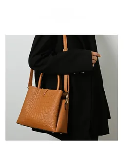 Brown crocodile pattern handbag with gold V-logo and shoulder strap on model