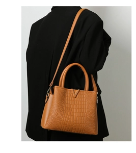 Detail of crocodile embossed leather tote with silver V hardware on a black blazer