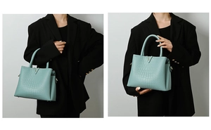 Detail of light blue crocodile embossed bag with gold V-shaped buckle and metal hardware
