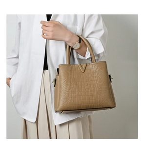 Detail of tan crocodile embossed tote bag with gold V-buckle and metal protective feet