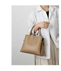 Close-up of khaki crocodile embossed texture with golden V-shaped metal hardware detail