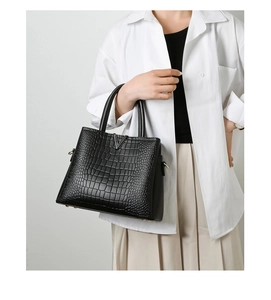 Detail of black crocodile texture handbag with silver V-shaped buckle and dual handles