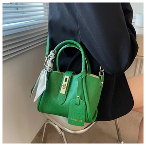 Détail du sac seau en cuir vert avec fermoir doré et poignée en foulard de soie imprimé