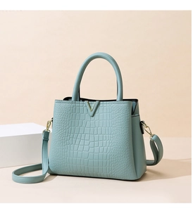 Close-up of light blue crocodile pattern texture and golden V-shaped metal hardware