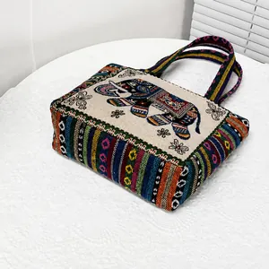 Bordado detallado de motivos de elefantes coloridos y flores en bolso de lino beige