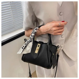 Détail du sac à main en cuir noir avec fermoir doré et poignée en foulard pied-de-poule