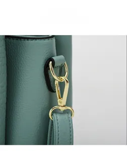 Detailed close-up of light green pebble grain leather texture and gold-tone metal hook