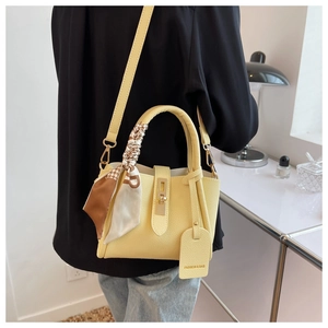 Détail du sac jaune à motif litchi avec foulard décoratif et boucle en métal doré