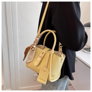 Détail du sac seau jaune avec foulard en soie à motif et fermoir rotatif doré brillant