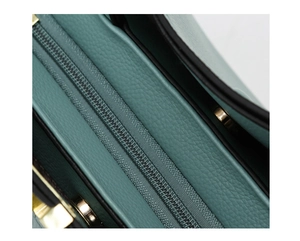 Detailed close-up of mint green pebble leather texture and gold-toned zipper on a handbag