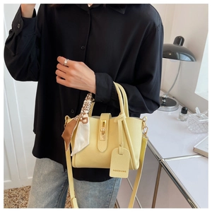 Détail du sac seau en cuir jaune avec poignée en foulard de soie et boucle en métal