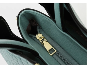 Close-up of mint green lychee grain leather with premium gold metal zipper and black edges