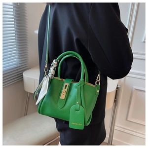 Détail du sac seau en cuir grainé vert avec fermoir doré et foulard en soie imprimé