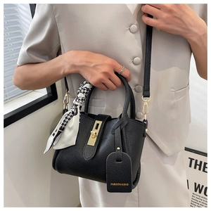 Détail du sac seau noir en cuir grainé avec fermoir doré et foulard pied-de-poule