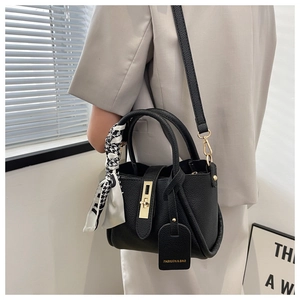 Détail d'un sac seau en cuir grainé noir avec foulard en soie et finitions dorées