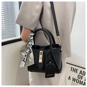 Détail du sac seau noir en cuir avec fermoir doré et poignée ornée d'un foulard en soie