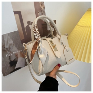 Détail du sac seau en cuir grainé crème avec fermoir doré et foulard en soie imprimé
