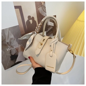 Détail du sac seau crème avec poignée ornée d'un foulard en soie et fini grainé