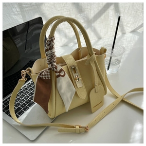 Détail d'un sac seau en cuir jaune avec foulard pied-de-poule et fermoir métallique