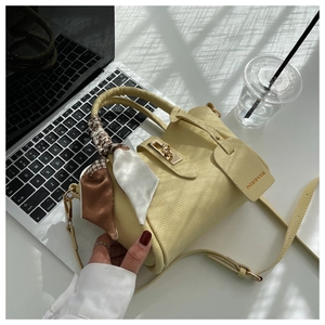 Détail du sac seau en cuir jaune avec foulard en soie et fermoir rotatif en métal