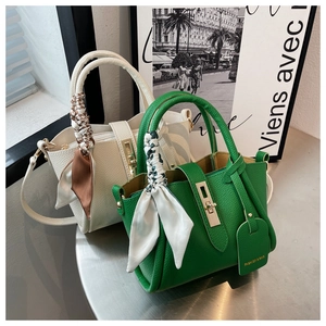 Détail de sacs bandoulière en cuir vert et blanc avec poignées en soie et fermoir doré