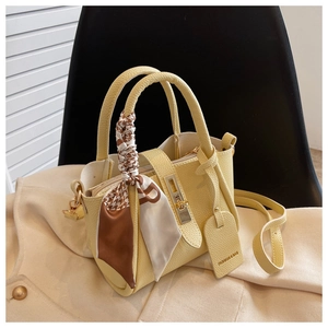 Détail du sac seau en cuir jaune pâle avec foulard en soie à motif pied-de-poule
