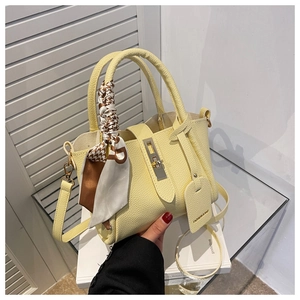 Détail du sac seau en cuir jaune clair avec fermoir doré et foulard en soie à motifs